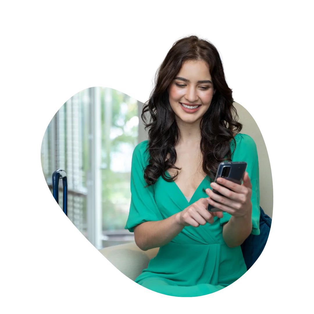 Smiling woman in green dress checking phone in hotel lobby
