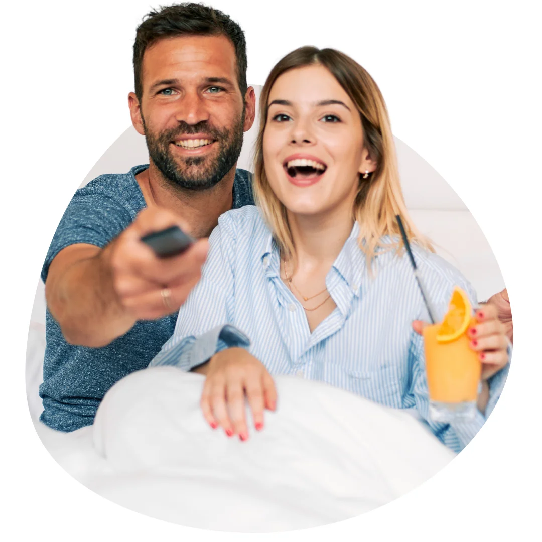 Happy couple relaxing together in a hotel room, enjoying entertainment with refreshments and smiling